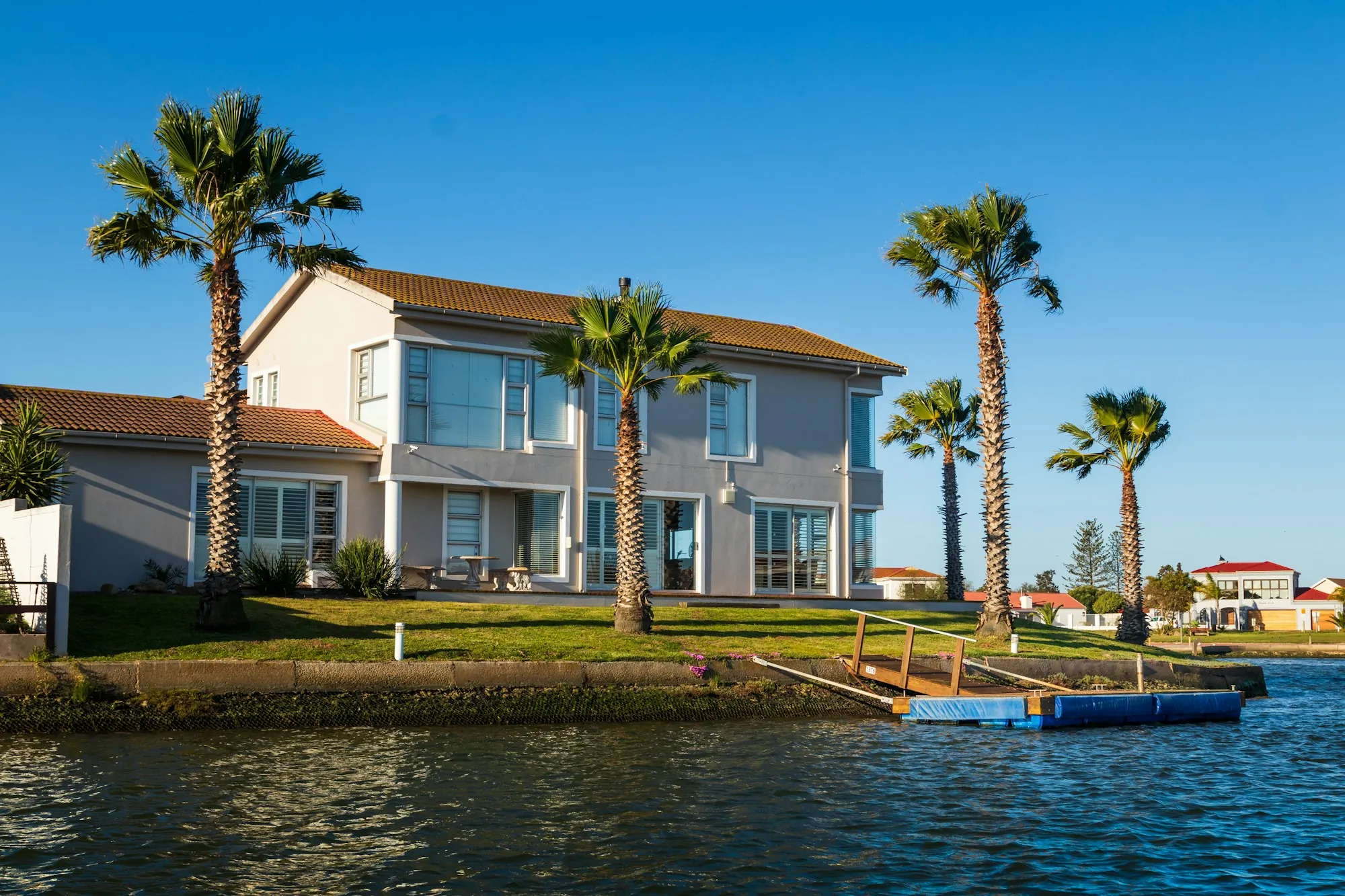 Two-story waterfront home with palm trees and a private dock